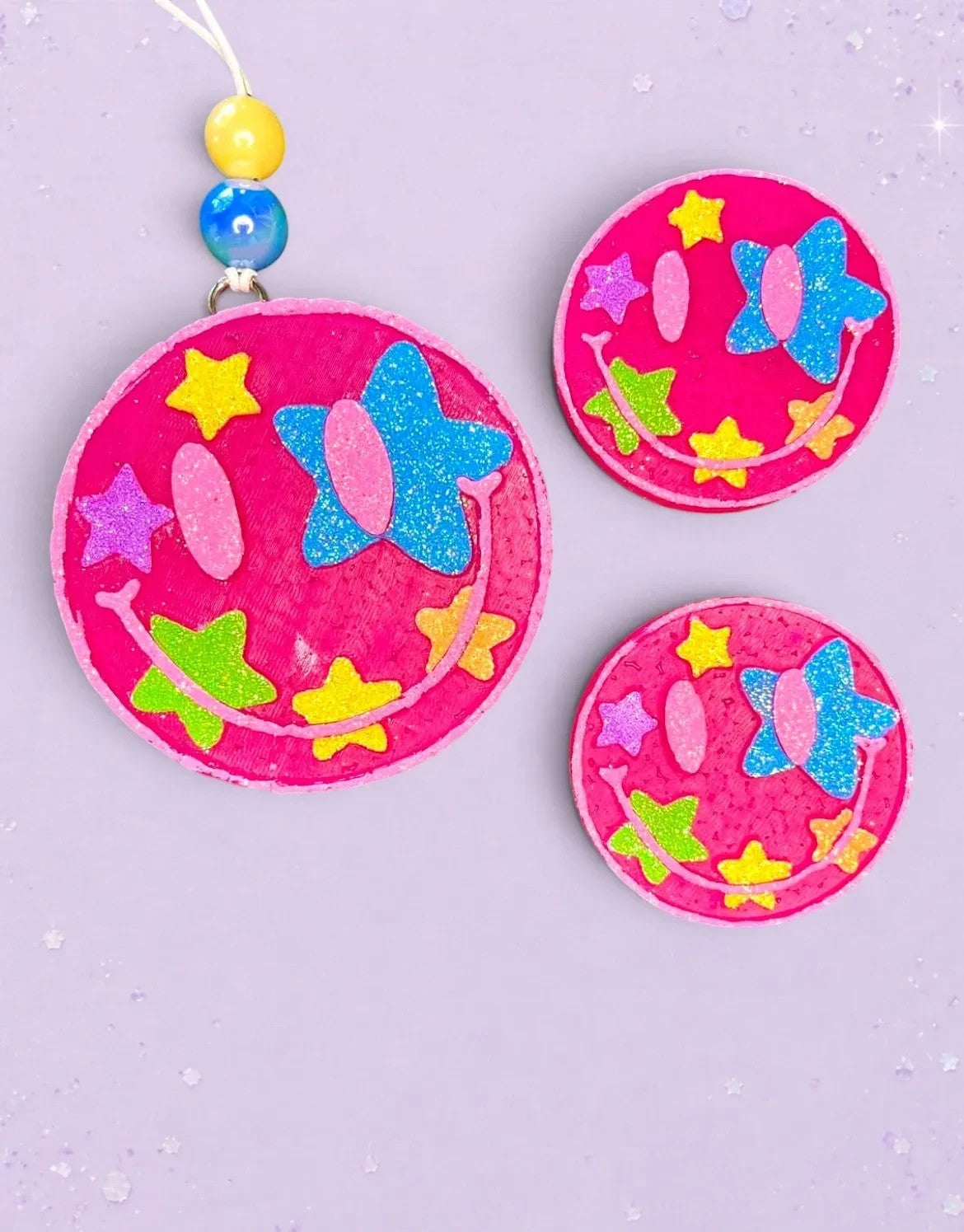 BeFreshie pink smiley face freshie with glitter stars and blue bow detail. Includes beaded string.