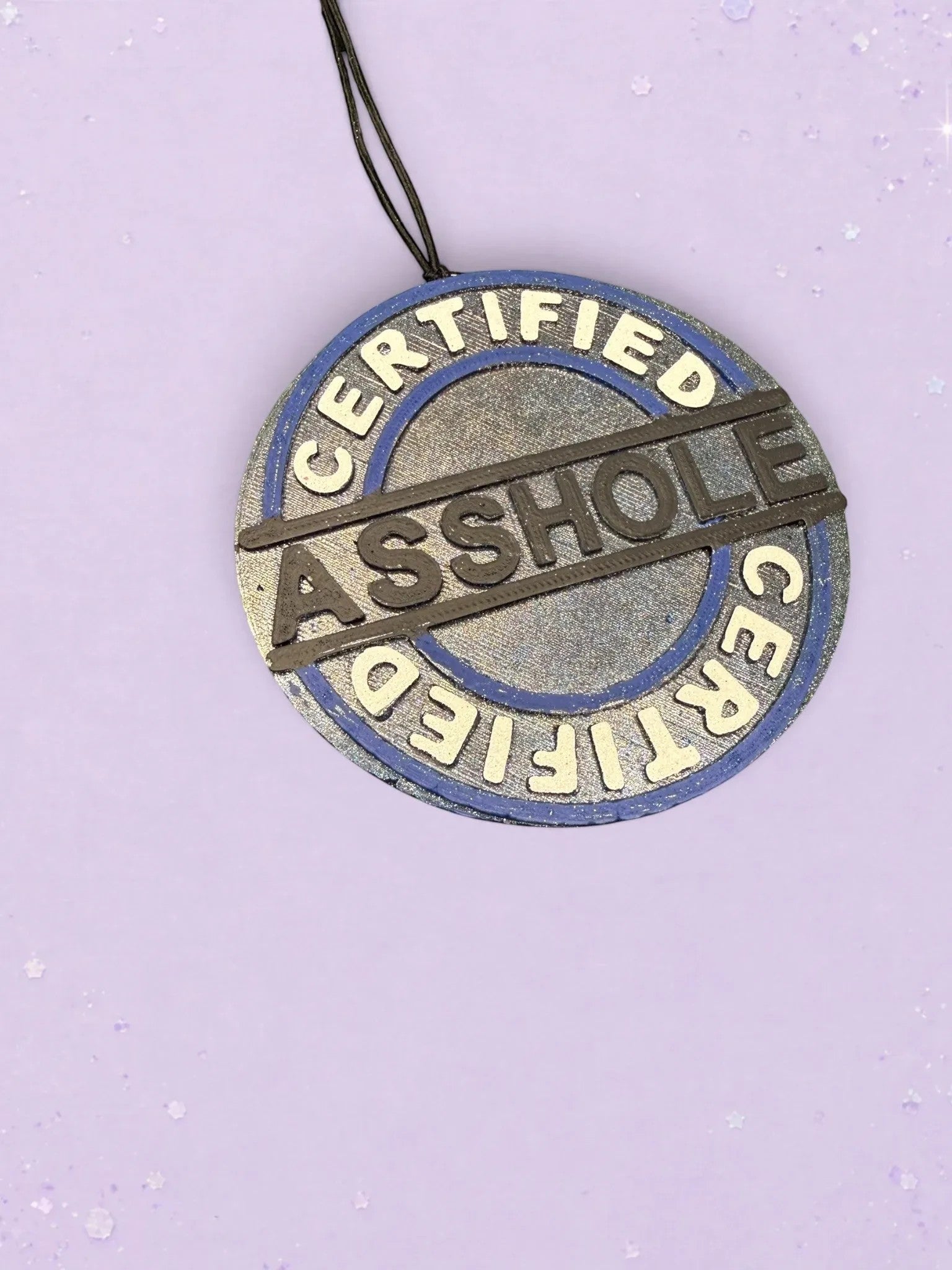 BeFreshie Certified Asshole car air freshener with a blue and silver circular design on a light purple background.