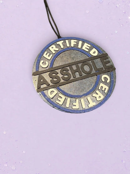 BeFreshie Certified Asshole car air freshener with a blue and silver circular design on a light purple background.