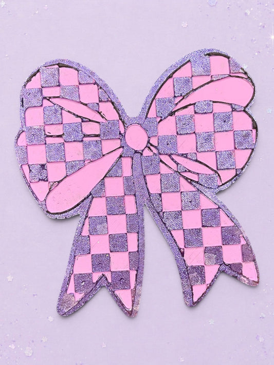BeFreshie checkered bow car freshie in glittery pink and purple on a matching pastel background.