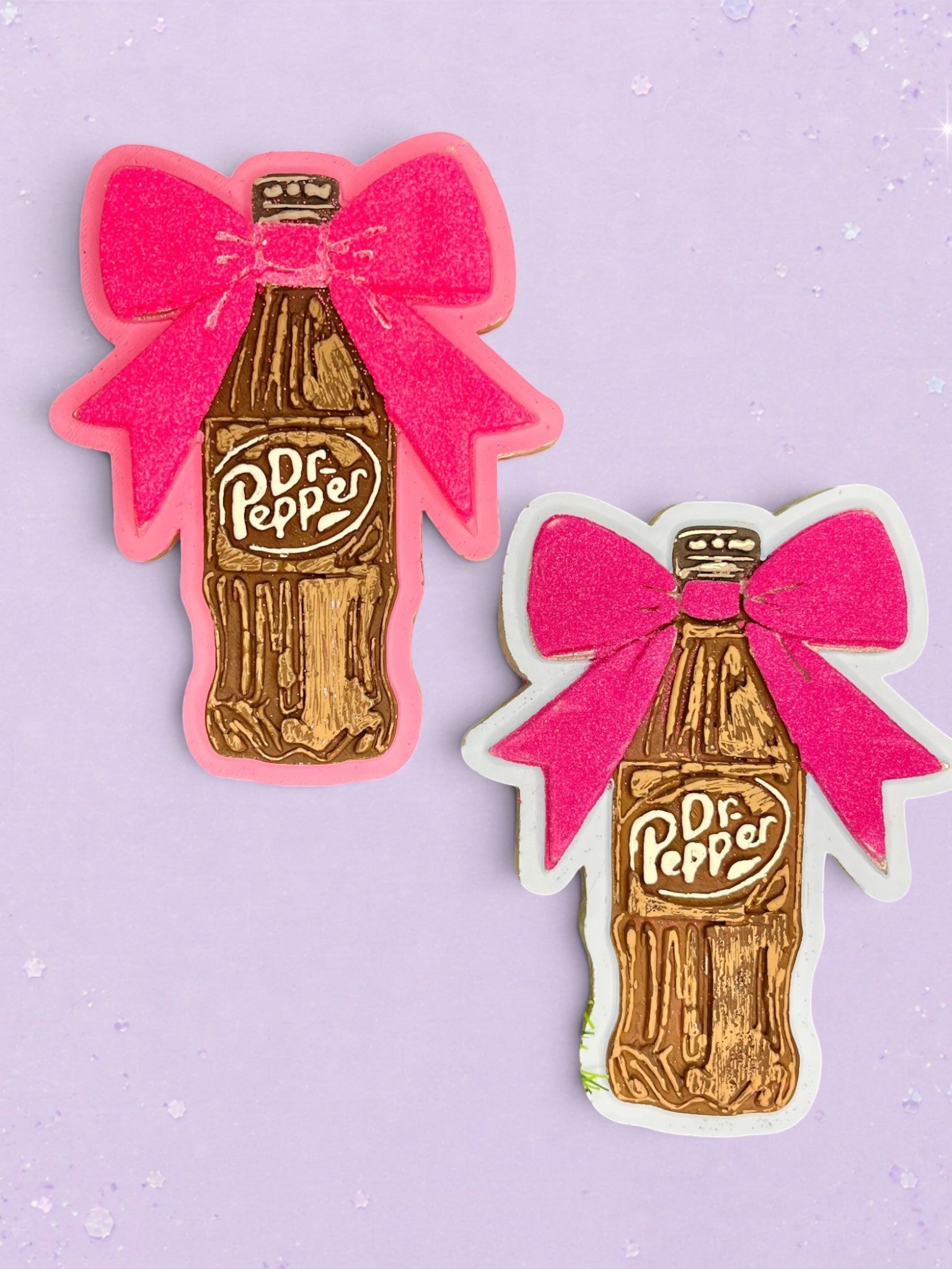 Two BeFreshie Dr Pepper bottle car freshies with bright pink bows on a light purple background