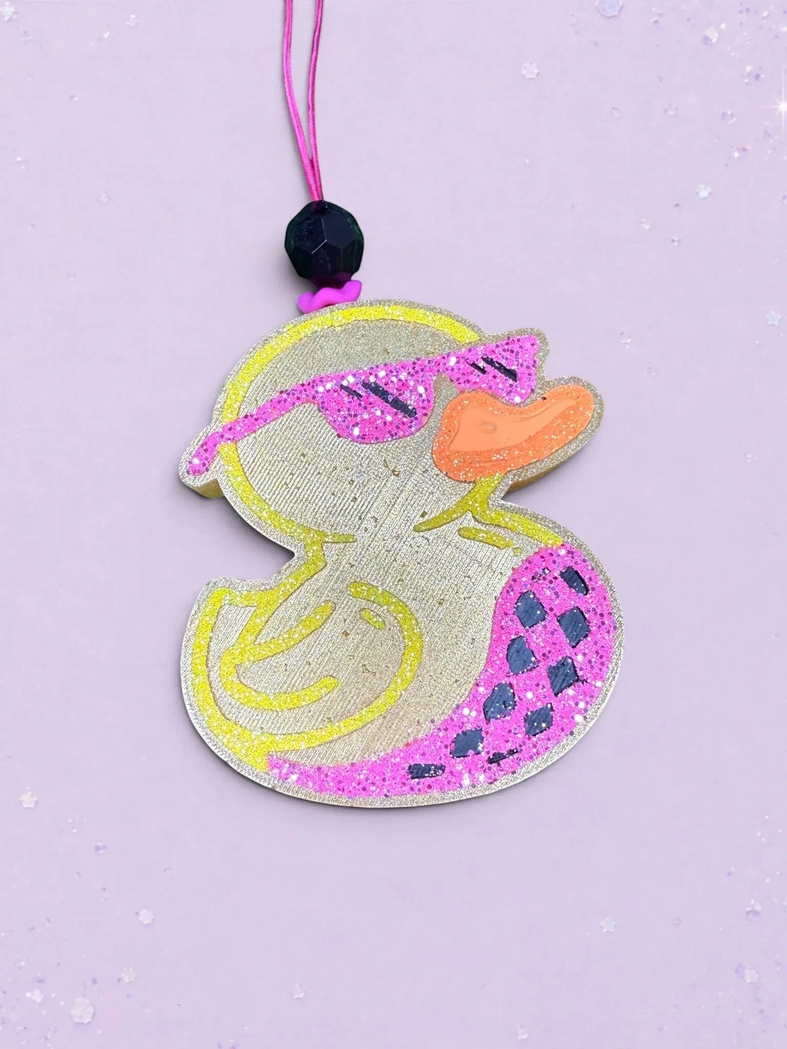 BeFreshie duck shaped car air freshener with glittery pink sunglasses and patterned wing on a purple background