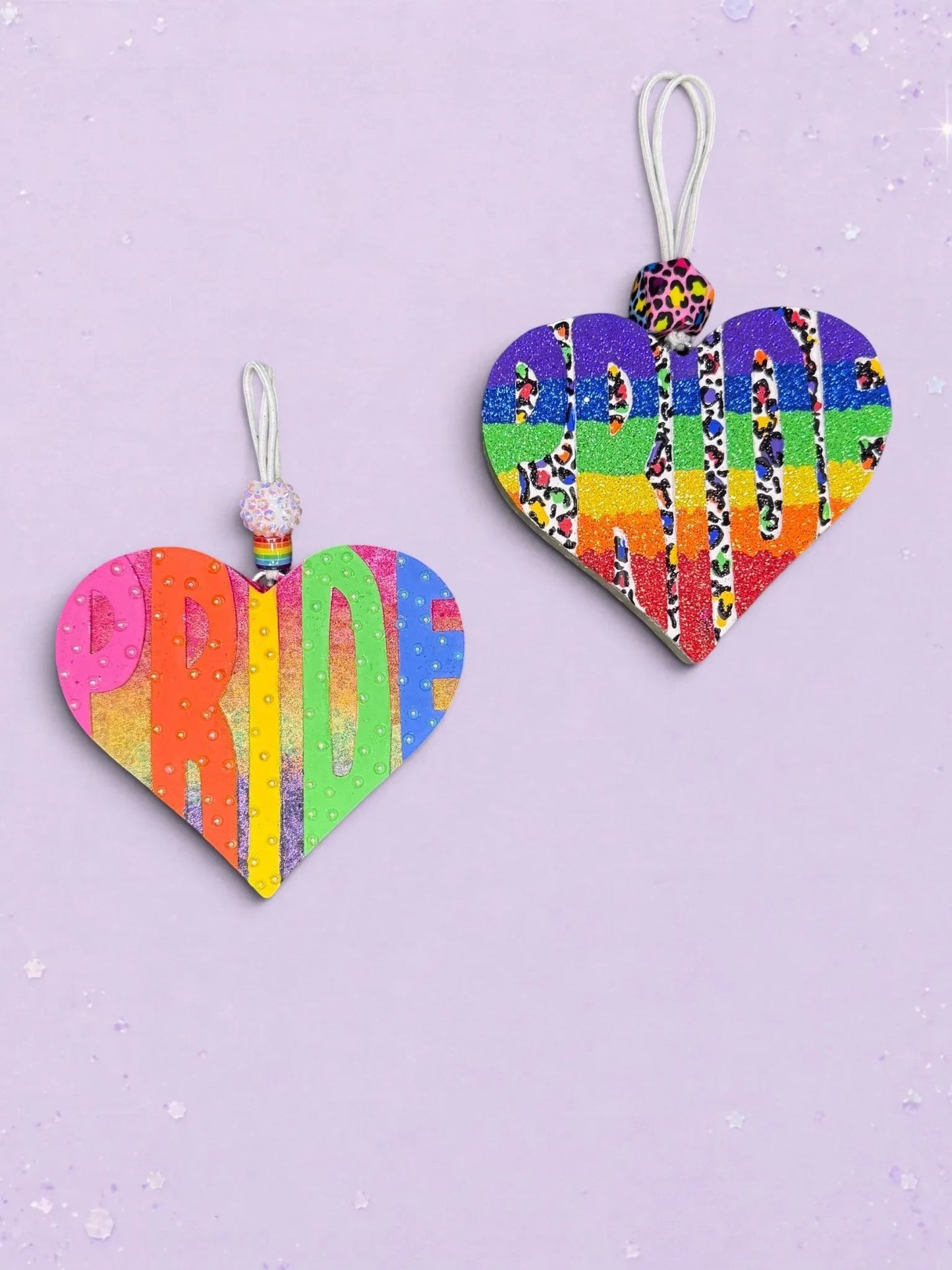 Two BeFreshie heart-shaped PRIDE car air fresheners featuring vibrant rainbow stripes, glitter, and leopard print accents.