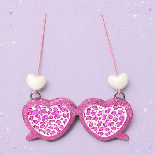 BeFreshie pink glitter heart-shaped sunglasses with leopard print lenses and white heart charms.
