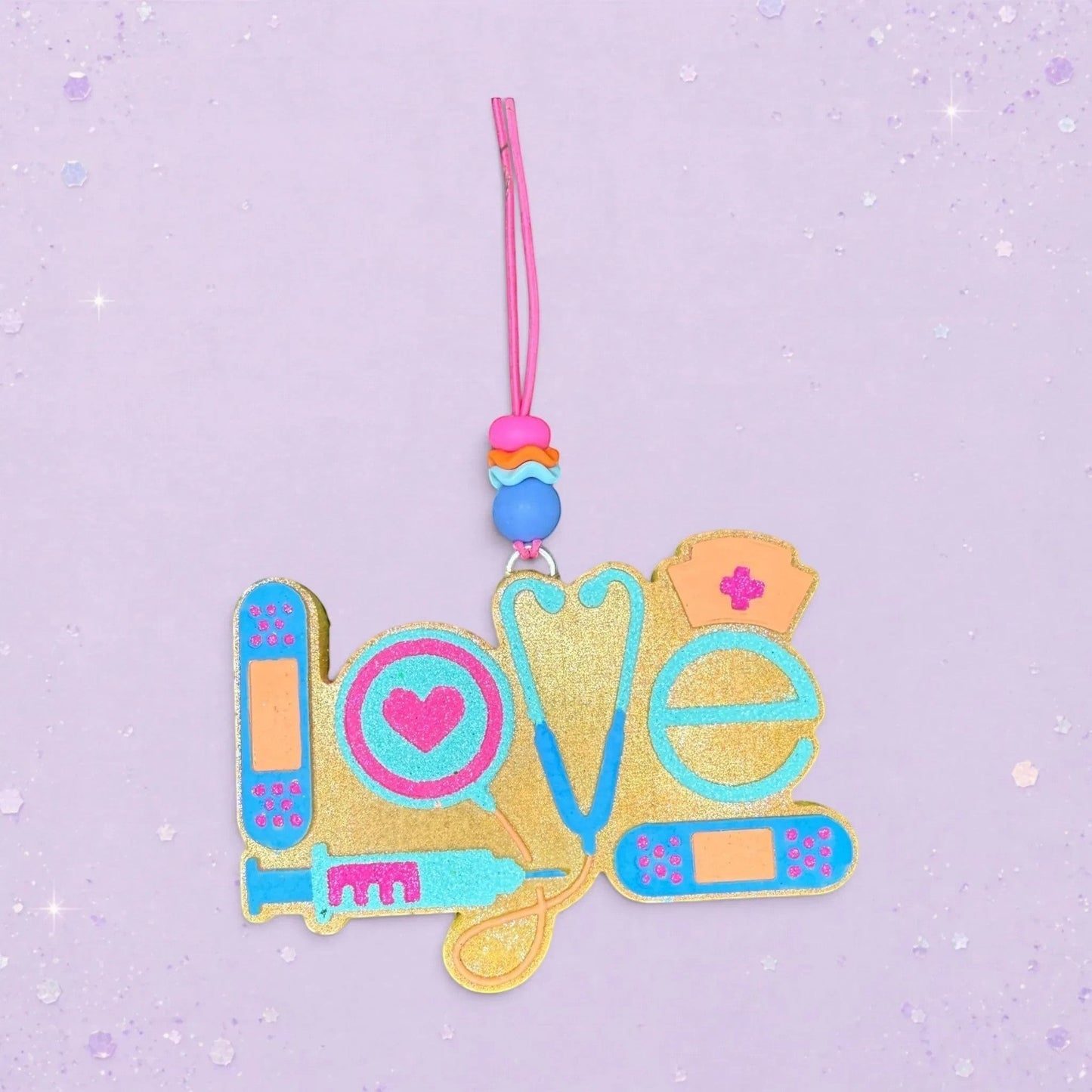 BeFreshie gold glitter "Love" freshie with medical icons: stethoscope, syringe, heart, nurse cap, and bandages.