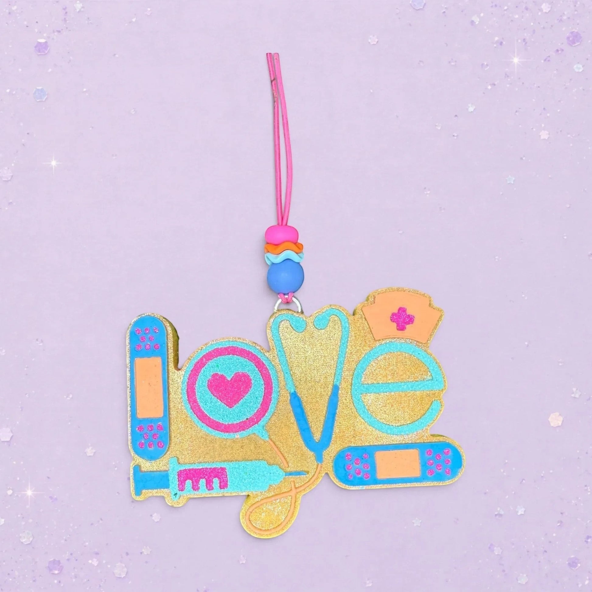 BeFreshie gold glitter "Love" freshie with medical icons: stethoscope, syringe, heart, nurse cap, and bandages.