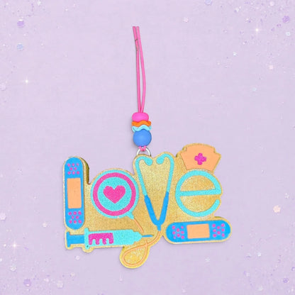 BeFreshie gold glitter "Love" freshie with medical icons: stethoscope, syringe, heart, nurse cap, and bandages.