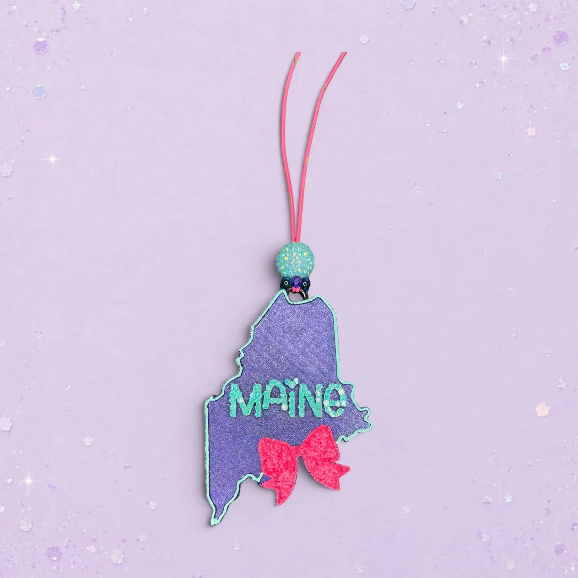 BeFreshie Maine state shape freshie with glitter, teal lettering, and a pink bow.
