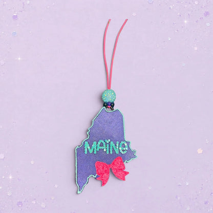 BeFreshie Maine state shape freshie with glitter, teal lettering, and a pink bow.