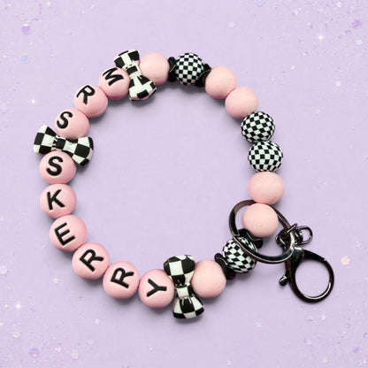 BeFreshie pink beaded keychain with black letters spelling 'SKERRY', checkered bows, and checkered beads.
