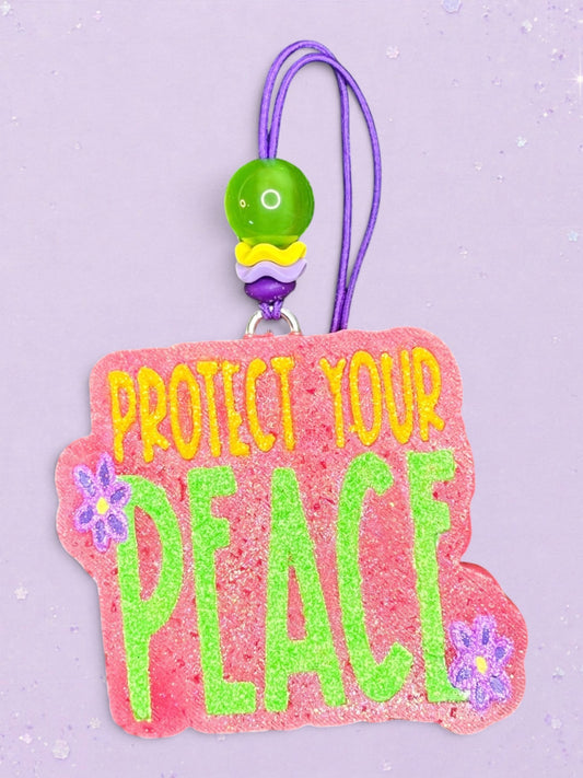 BeFreshie Protect Your Peace car freshie with pink glitter background, green text, and purple flower accents.