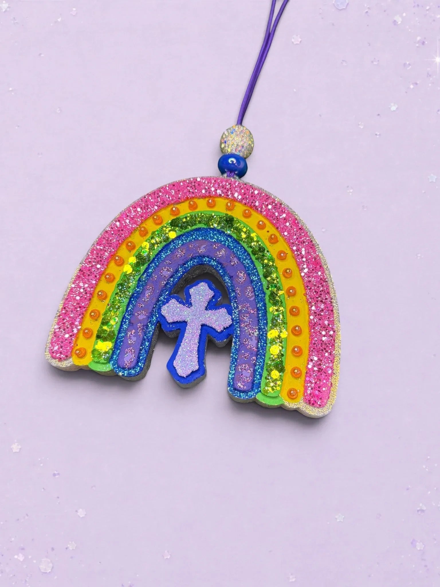 BeFreshie rainbow car freshie featuring a glittery multi-colored arch and a central purple cross on a purple string.