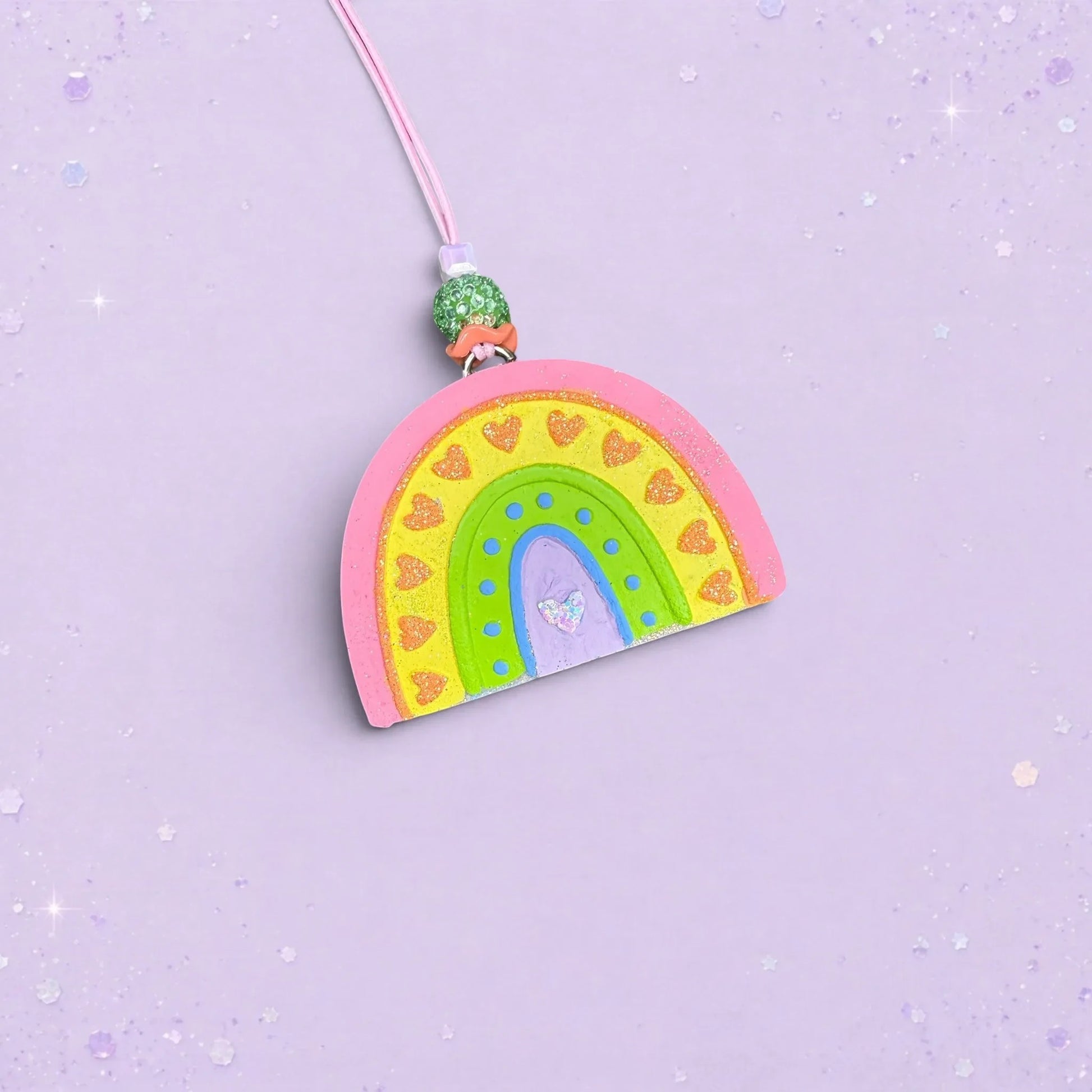 BeFreshie Rainbow Medium freshie with glittery heart patterns, hanging from a pink string on a purple background.