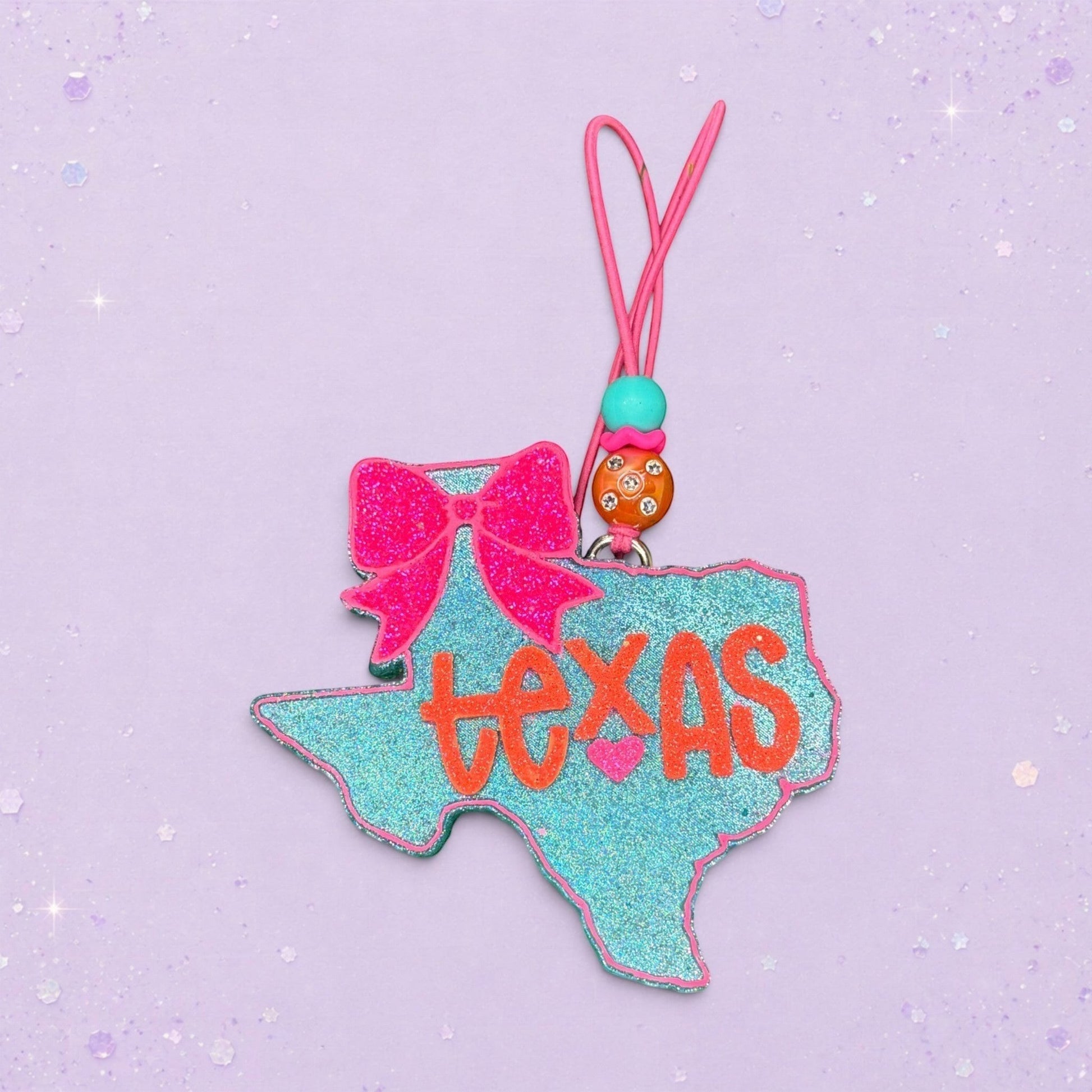 BeFreshie Texas shaped freshie with glittery teal finish, hot pink bow, and orange "Texas" text. Includes pink cord.