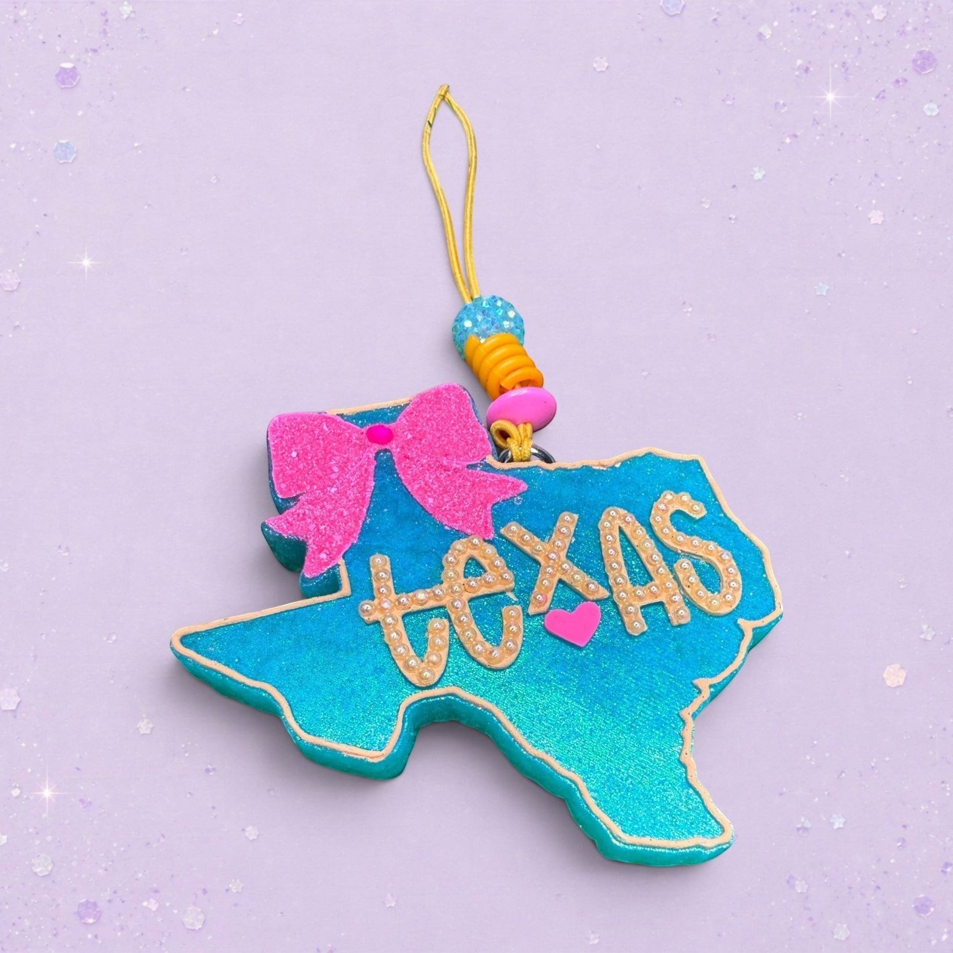 BeFreshie Texas shaped air freshener in turquoise glitter with a pink glitter bow and gold lettering. Features a small pink heart.